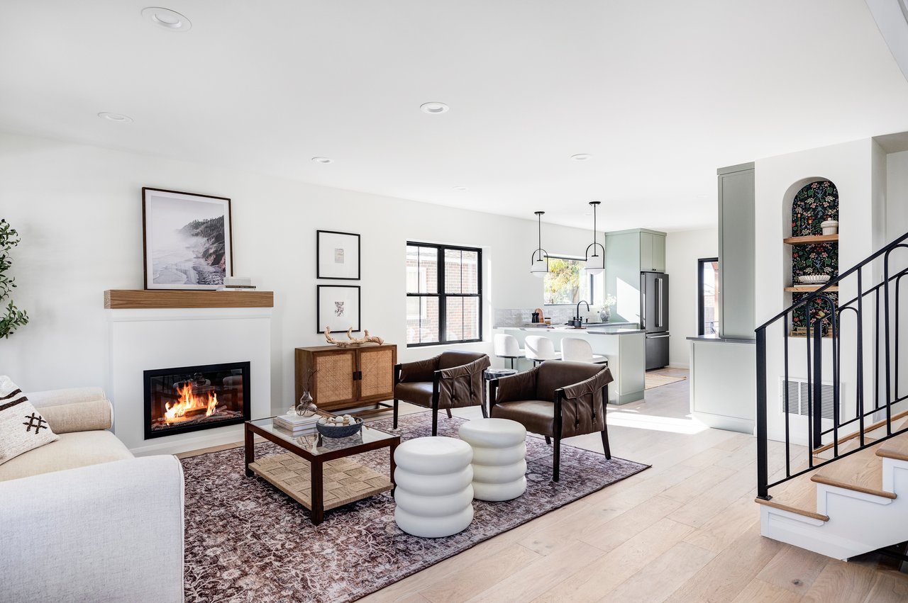 Contemporary living room with gas fireplace and wood shelf above, white and leather seating, open to kitchen