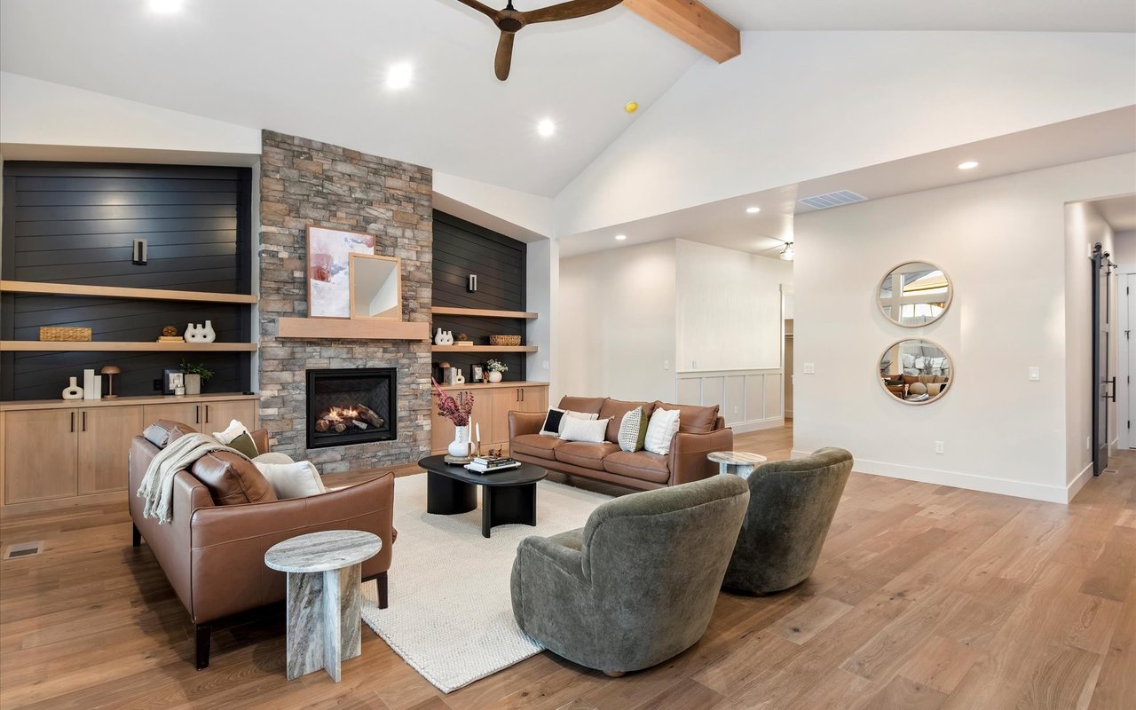 Living room with stone fireplace, oak built-ins, and wide-plank engineered hardwood flooring