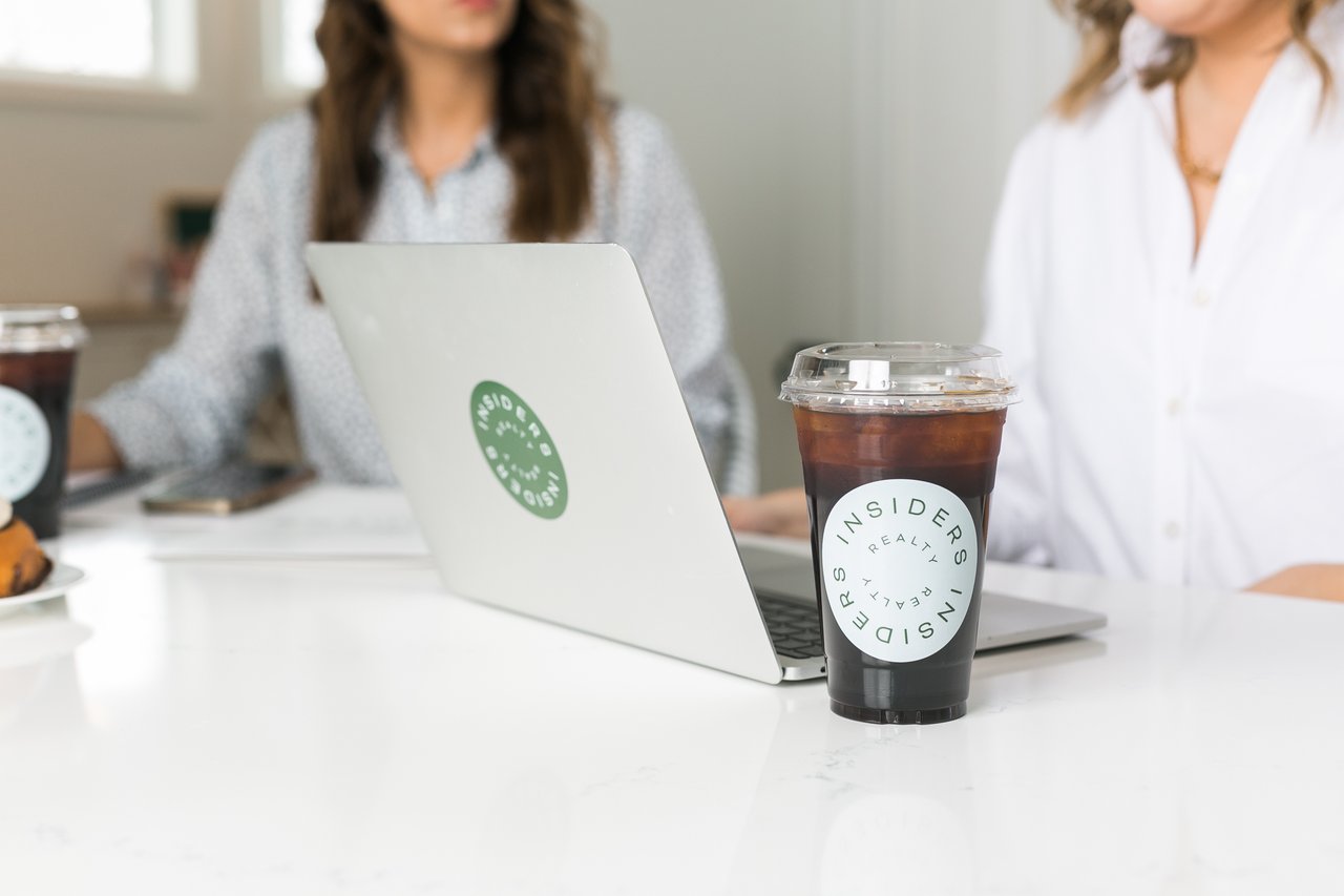 A laptop and coffee on a table as two people work through selling a family home in Madison from out of state.