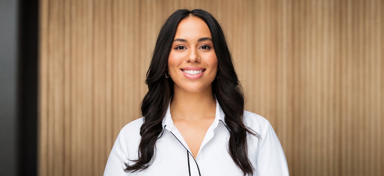 Yohanna Galleti smiling in a white blouse against a wood-paneled wall.