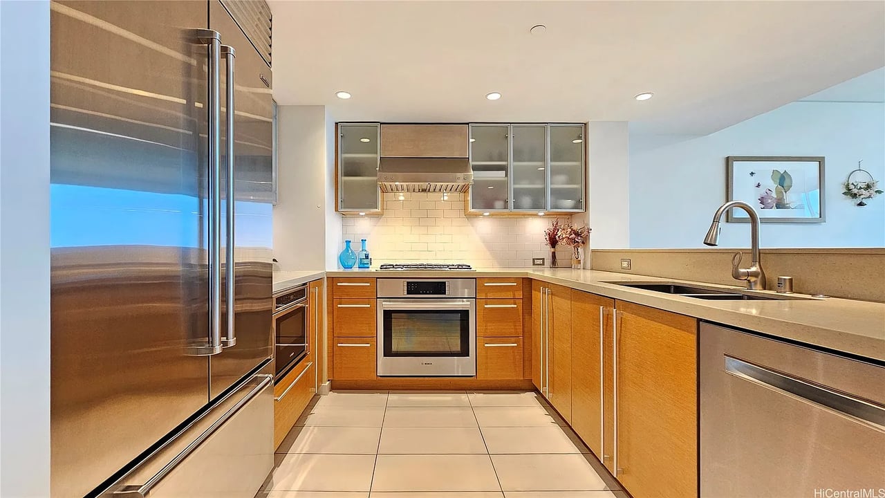 Modern kitchen with warm wood cabinets, stainless steel appliances, and stone countertops.