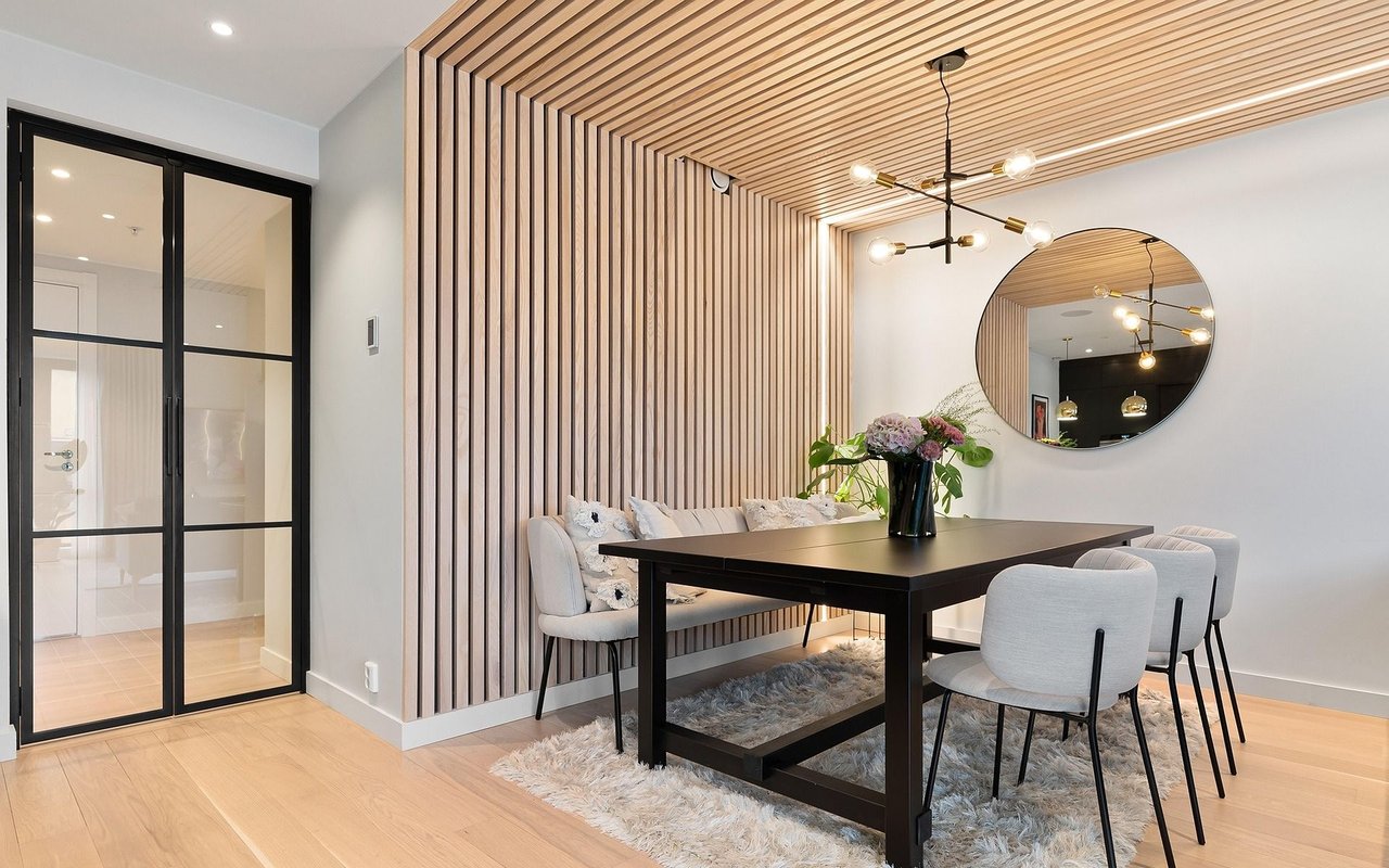 Modern dining room with a wood-slat accent wall and ceiling, black table, and glass doors.