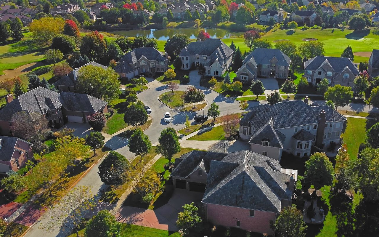 Aerial view of homes bordering a golf course and pond.