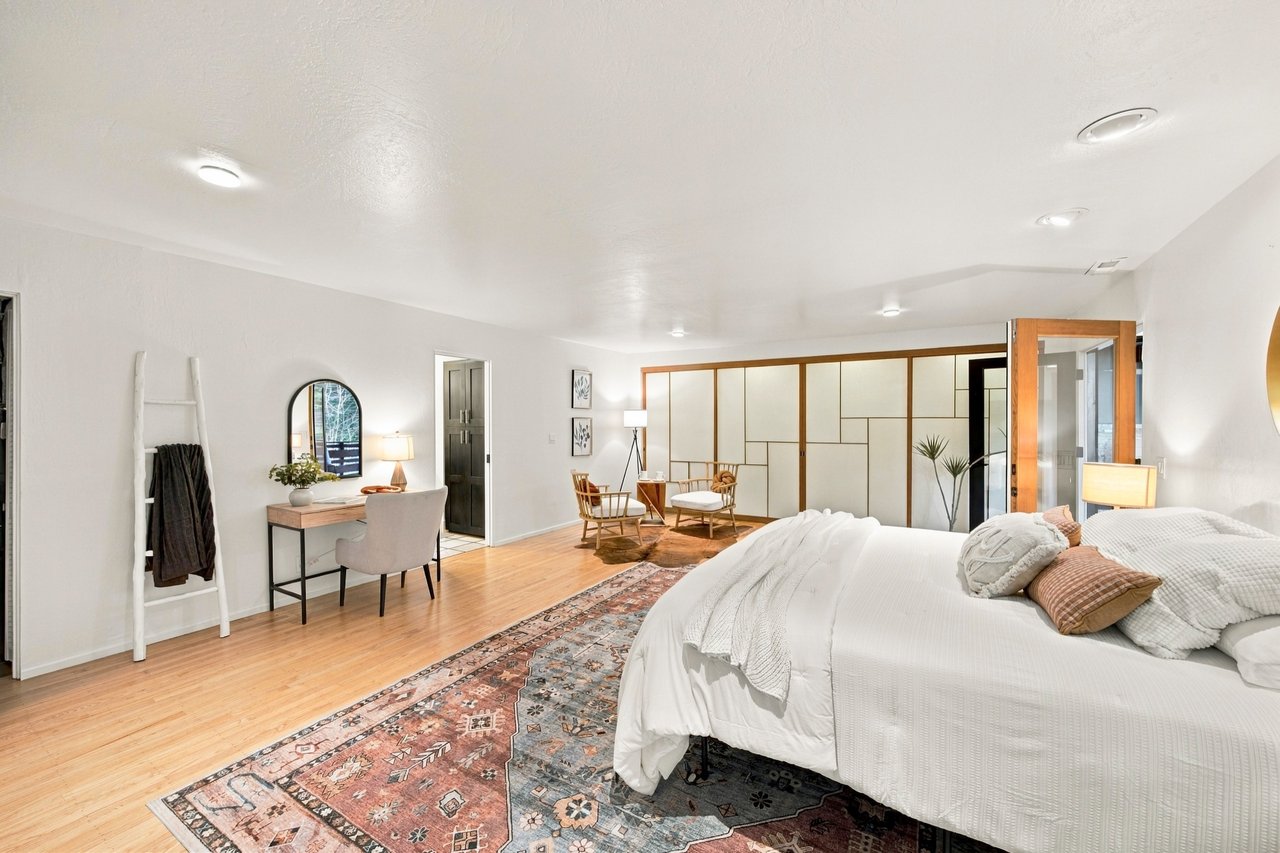 Bedroom with a large bed, patterned rugs, and a sitting area behind geometric room dividers.