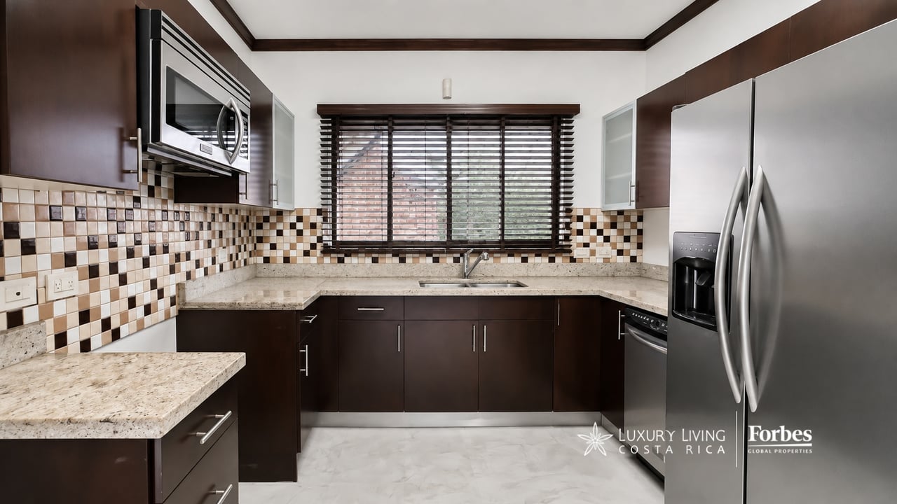 Kitchen with dark wood cabinets, granite counters, mosaic backsplash, and stainless steel appliances.