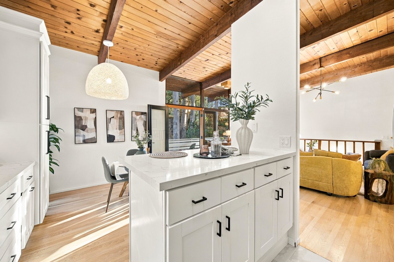 Bright kitchen with a large white island beneath a vaulted wood-plank ceiling.