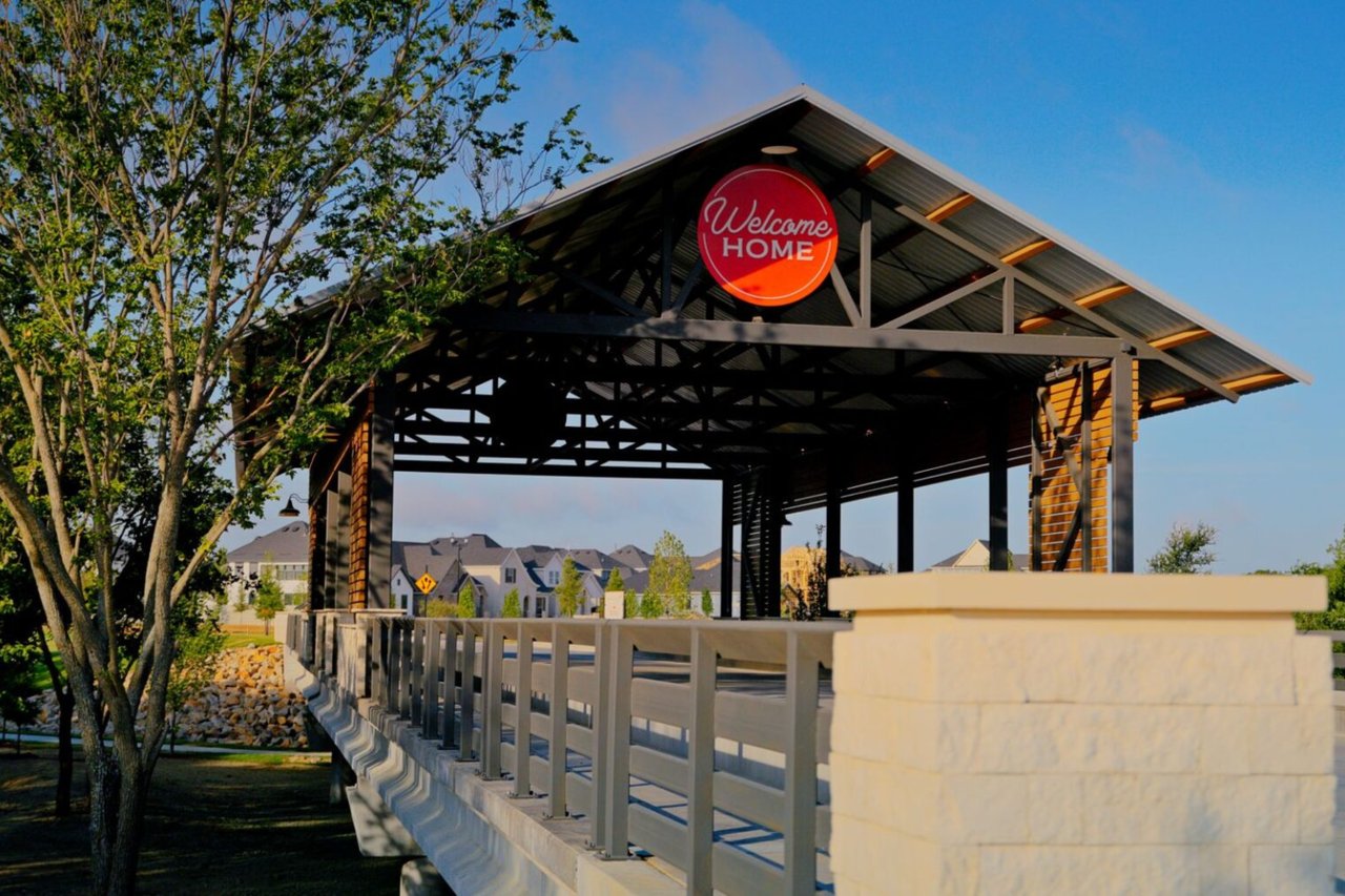 Entrance to the Treeline master‑planned community in Justin, Texas, featuring a covered bridge with a “Welcome Home” sign and newly built homes in the background.