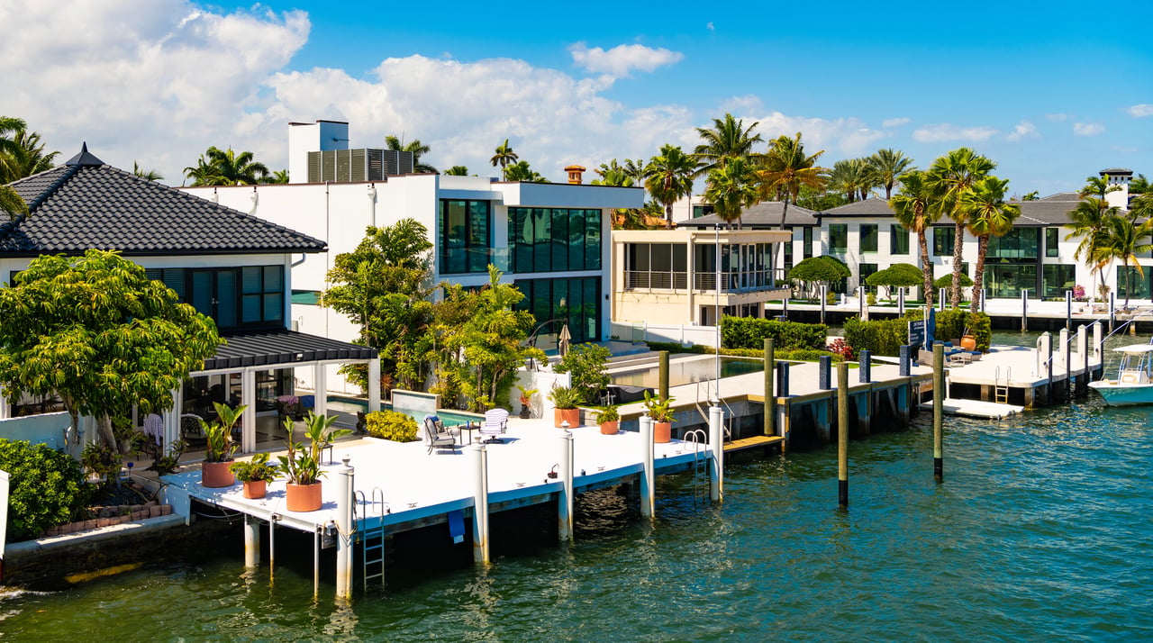 Waterfront homes with private docks and palm trees lining a sunny canal.