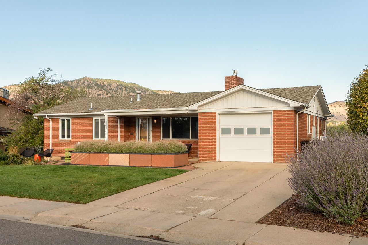 Front of the single-story brick home at 2003 Balsam Drive in Boulder with a driveway, garage, and foothill views