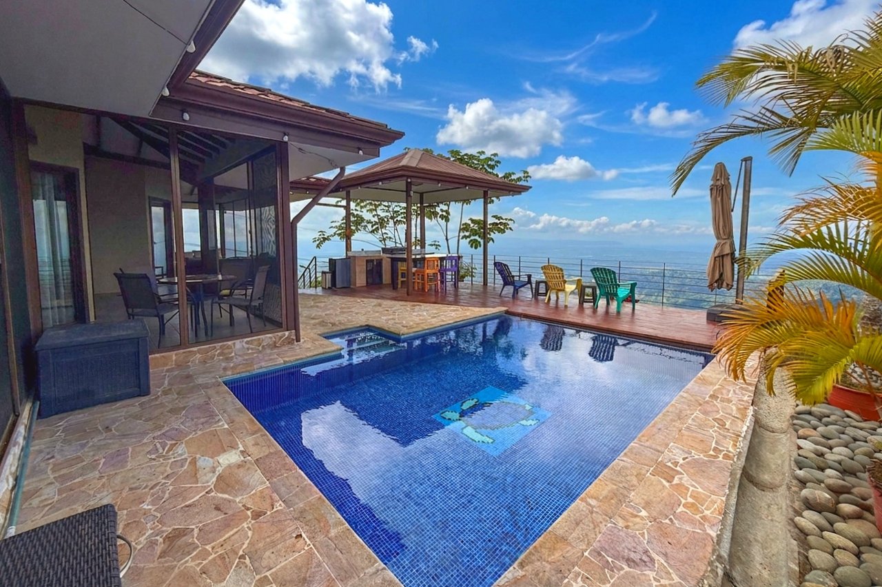 Outdoor pool with a stone patio and ocean view beside a modern home.