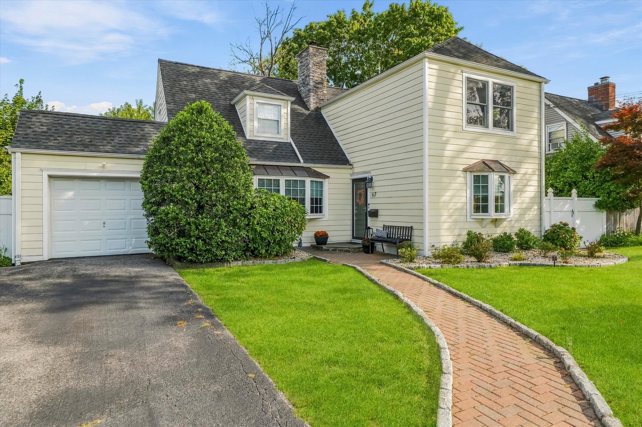 Cream two-story home with an attached garage and curved brick walkway across the front lawn.