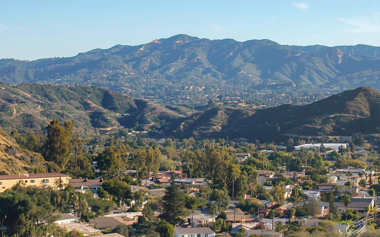 Poway neighborhood homes among rolling hills, with a mountain range in the distance.