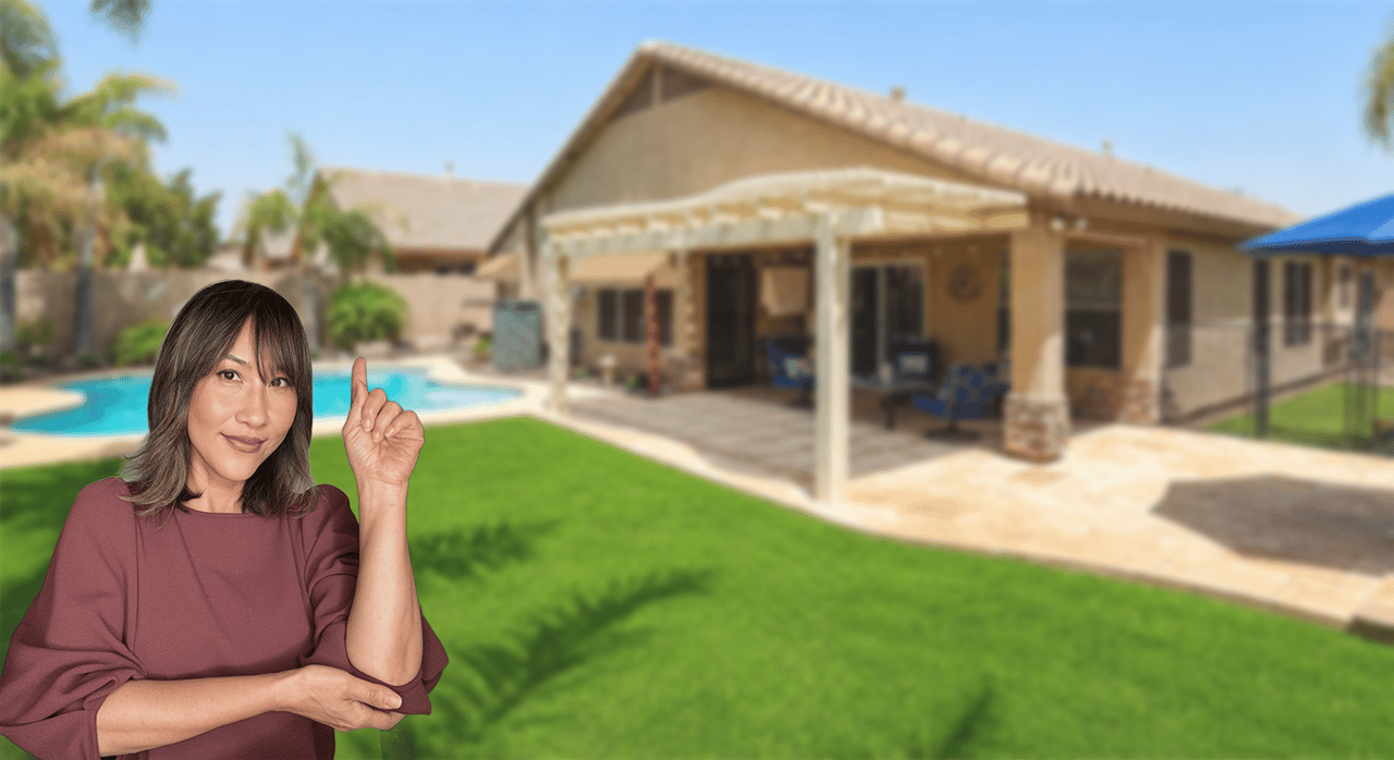 Woman points toward a single-story home with a covered patio and backyard pool.