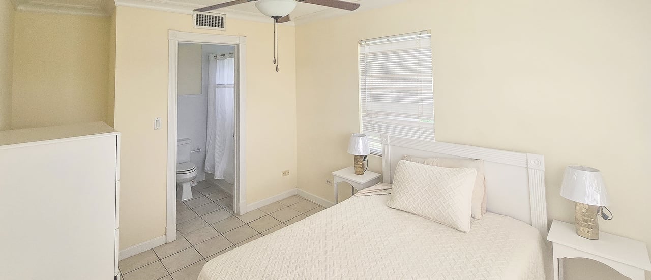 Bedroom with a white bed and an open doorway to the bathroom.