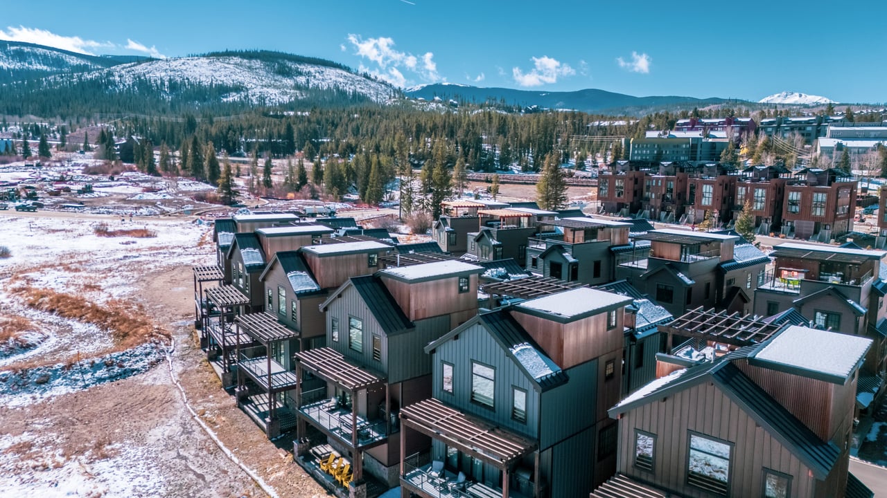 Aerial view of modern ROAM homes beneath snow-covered mountains in Winter Park.