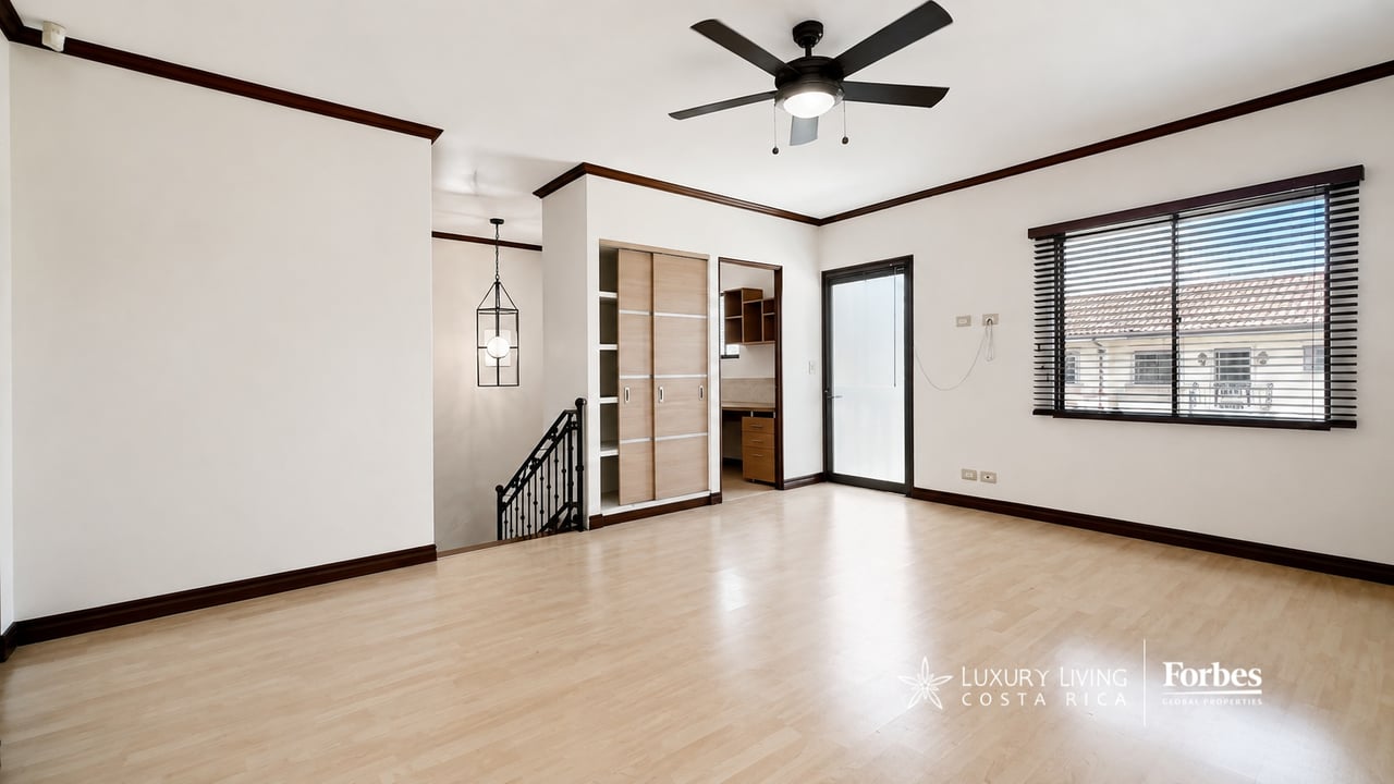 Vacant upstairs room with built-in desk, sliding closet doors, and a window with blinds.