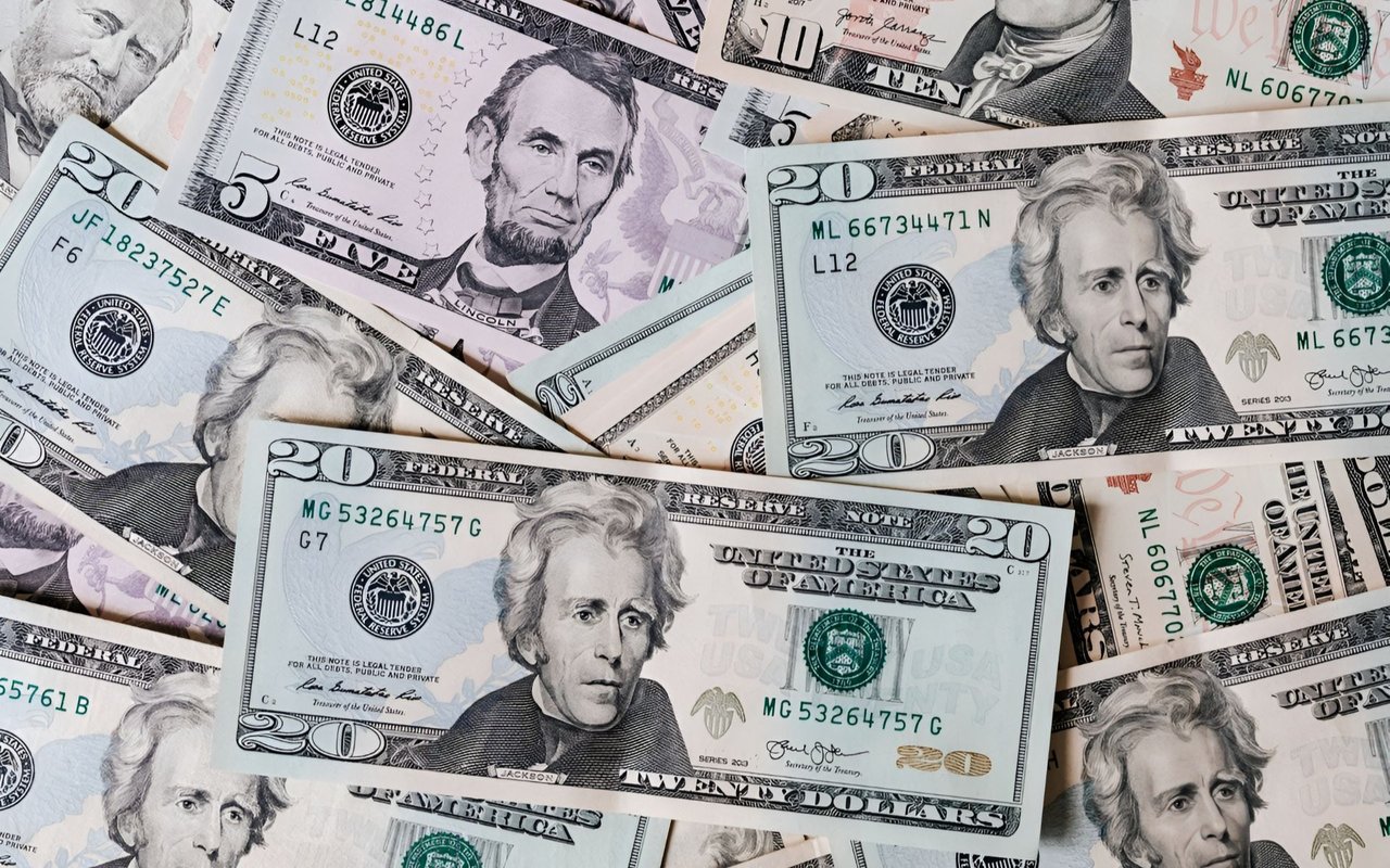 Overlapping U.S. banknotes, with Andrew Jackson on several twenty-dollar bills and Abraham Lincoln on a five-dollar bill.