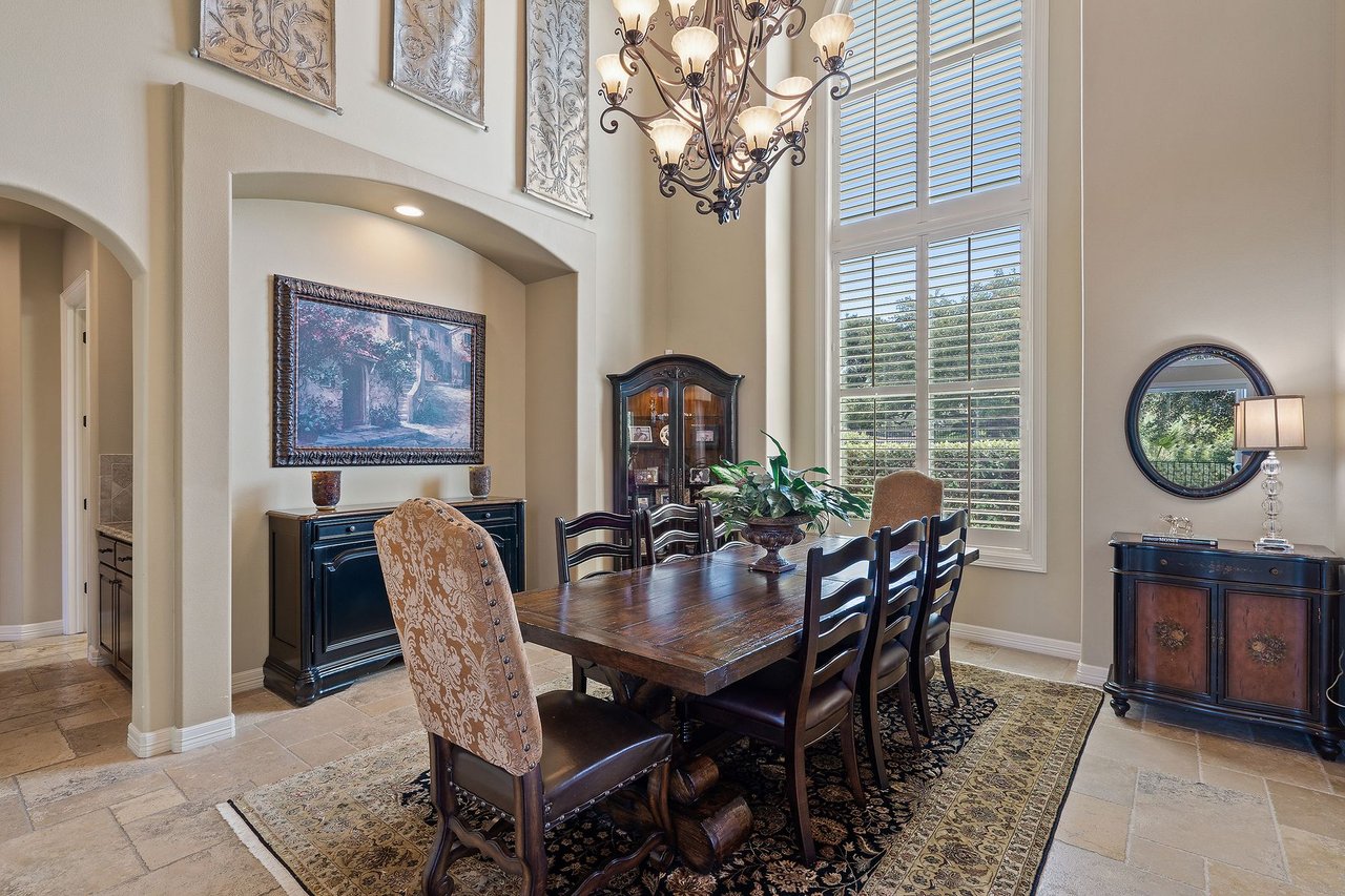 Formal dining room with a wood table, chandelier, and arched window at 25715 Cliff Circle, Lakecliff on Lake Travis, Spicewood, Texas.