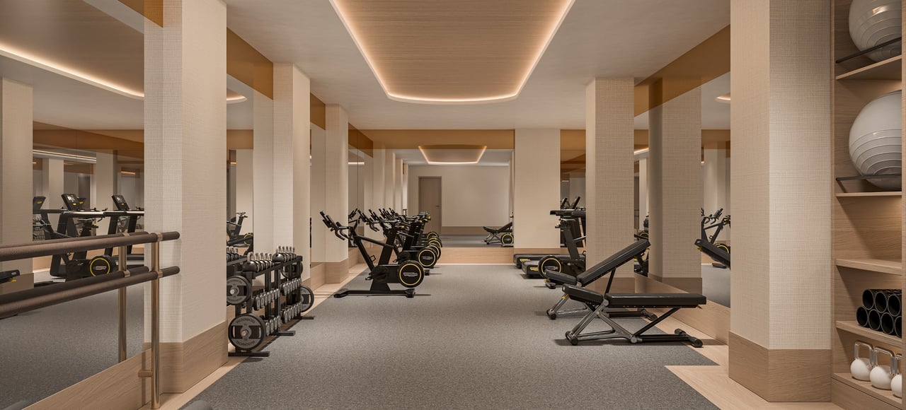 Fitness center with rows of exercise bikes, dumbbells, and weight benches.