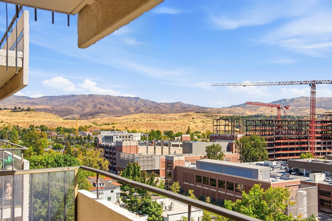 Balcony overlooking urban buildings under construction and dry foothills.