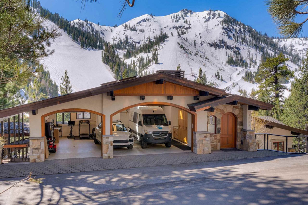 Mountain home with a timber-trimmed garage beneath snow-covered peaks.