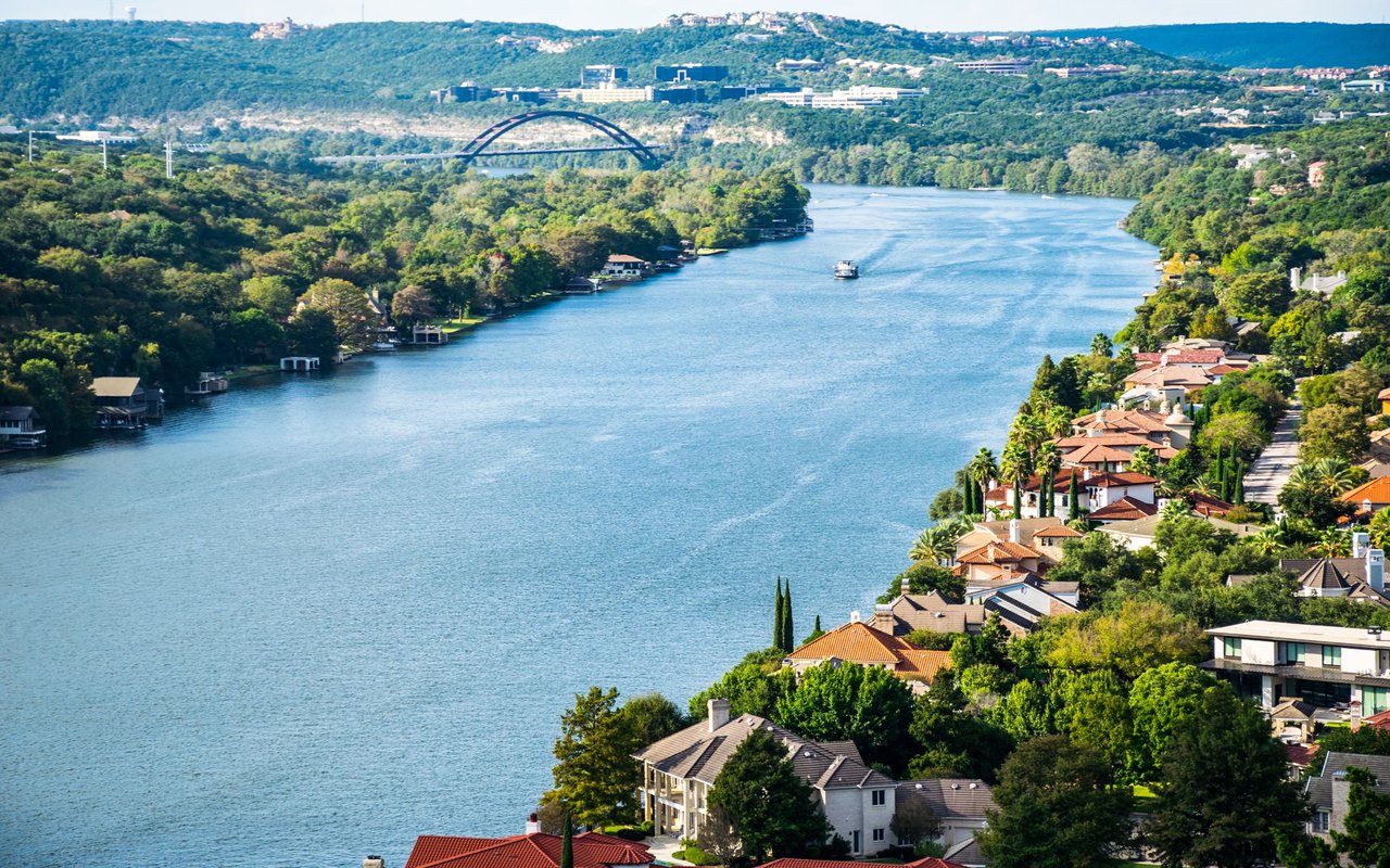 Lake Austin and waterfront homes, with the Pennybacker Bridge spanning wooded hills.