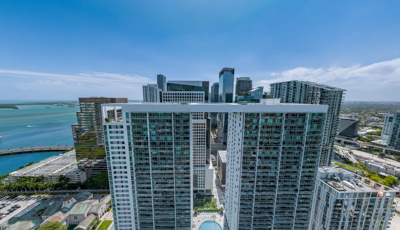Viceroy Brickell’s white-and-glass residential towers beside Biscayne Bay, with downtown Miami behind them.