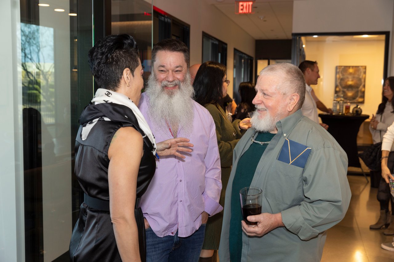 Guests chat at a client appreciation open house, with one holding a drink.