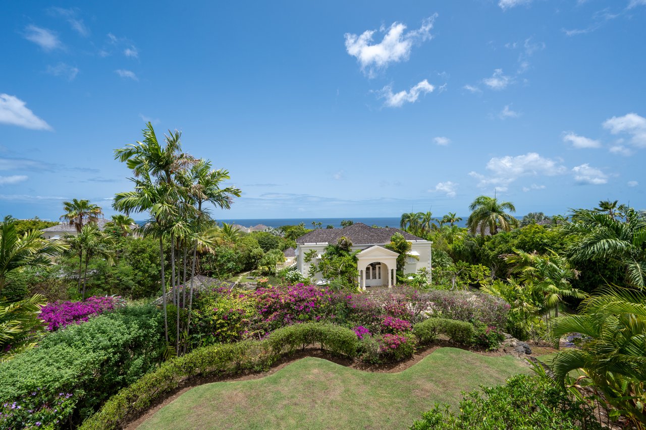 Coconut Ridge 4 villa framed by tropical gardens and palms, with the Caribbean Sea beyond.