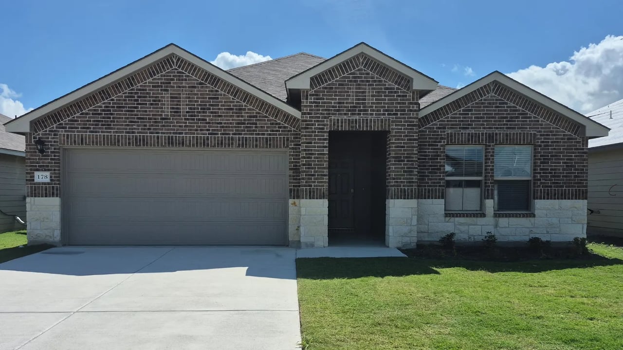 Single-story brick home with a two-car garage, covered entry, and front lawn.
