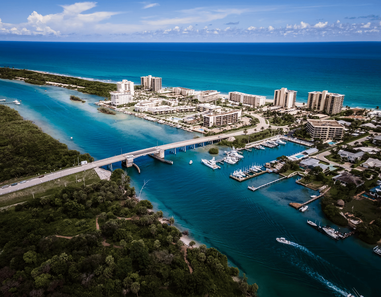 Aerial view of a coastal community, marina, and bridge beside the Atlantic Ocean.
