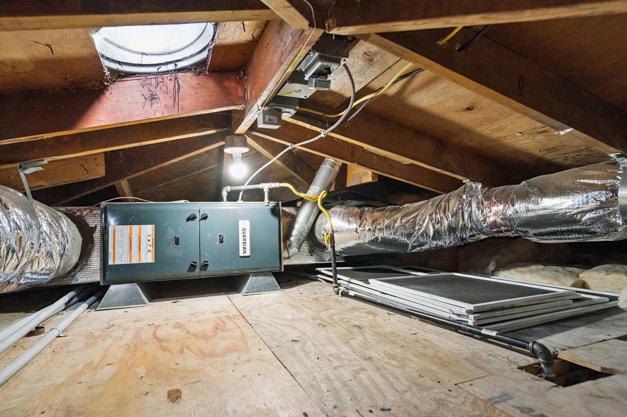Attic HVAC system with a Guardian unit, insulated ducts, exposed rafters, and stacked panels.