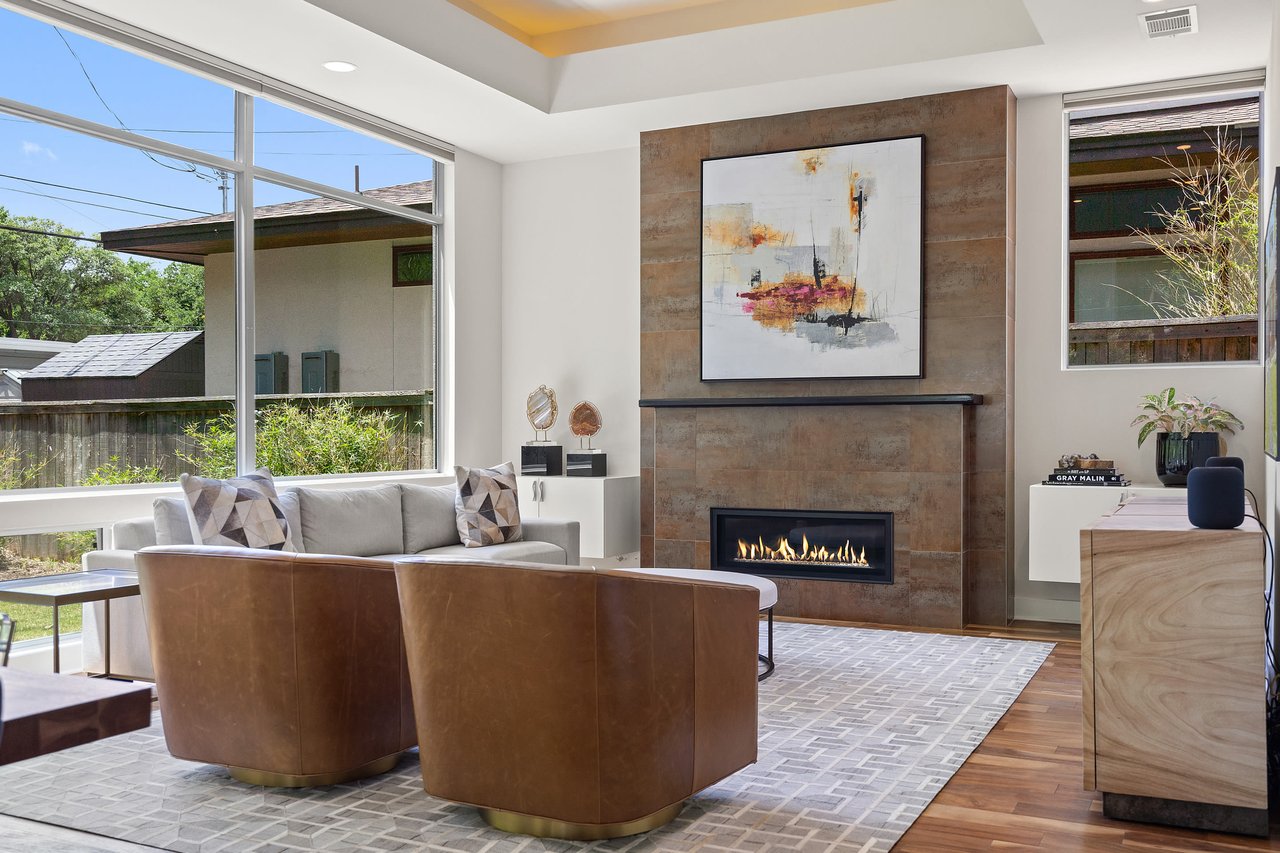 Living room with a fireplace, tray ceiling, and wood accent wall at 34 Margranita Crescent, Tarrytown, Austin, TX.