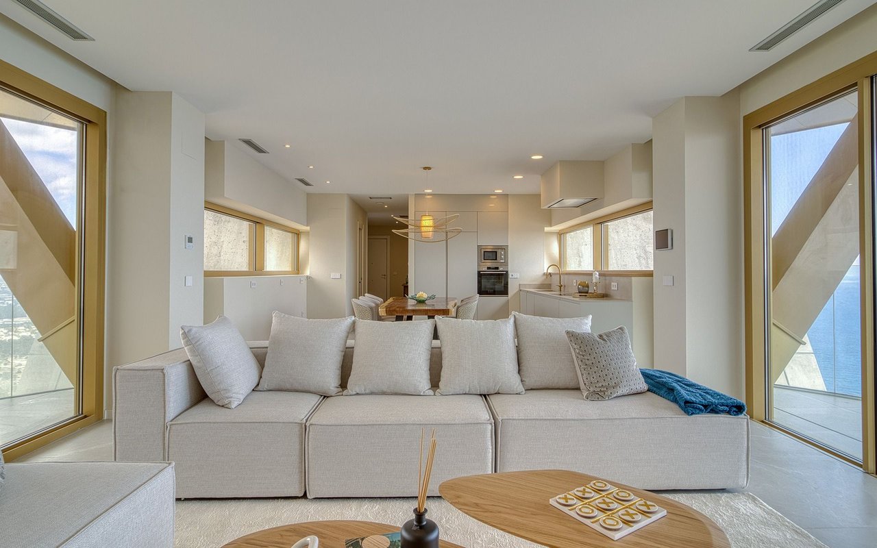 Open-plan living room with a large sectional sofa, round coffee table, and kitchen beyond.