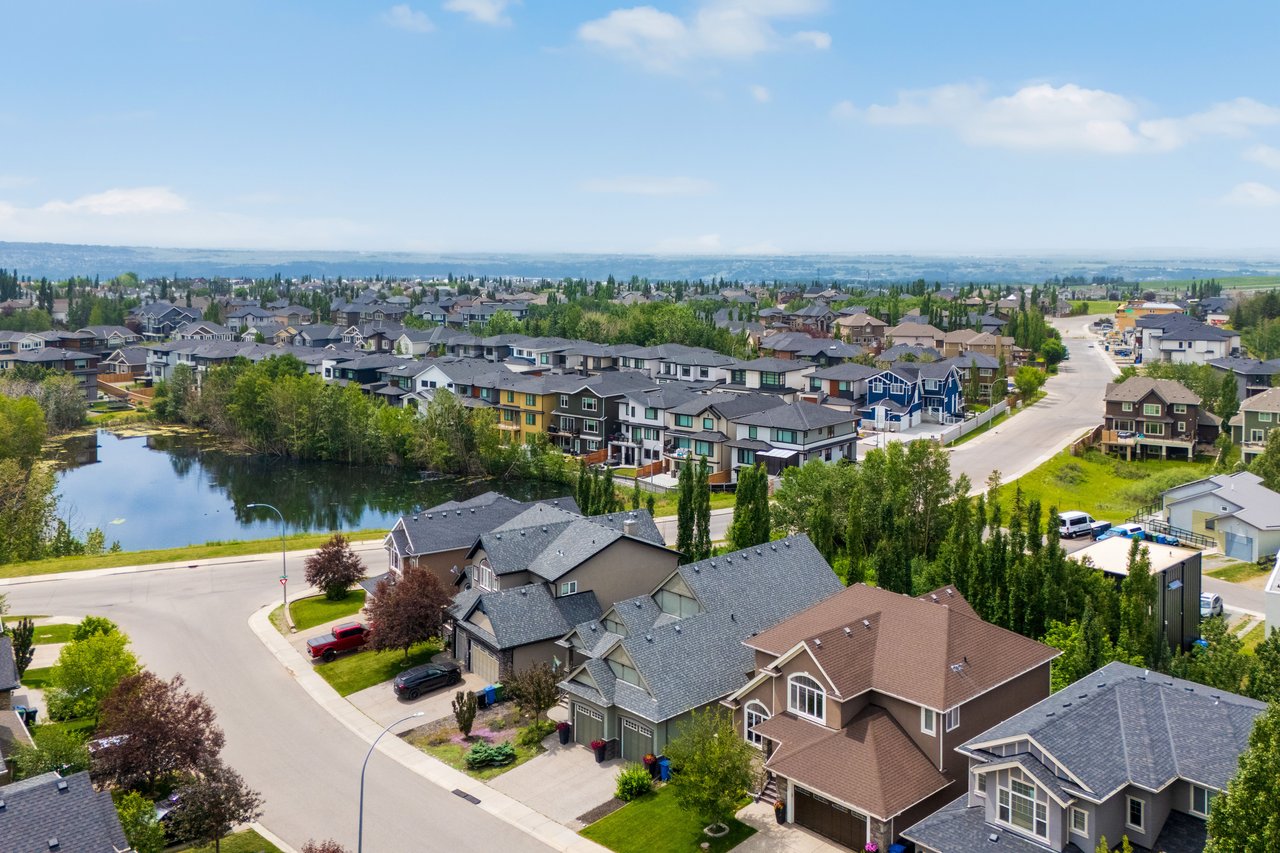 Aerial view of homes, trees and a pond in Rocky Ridge, northwest Calgary.