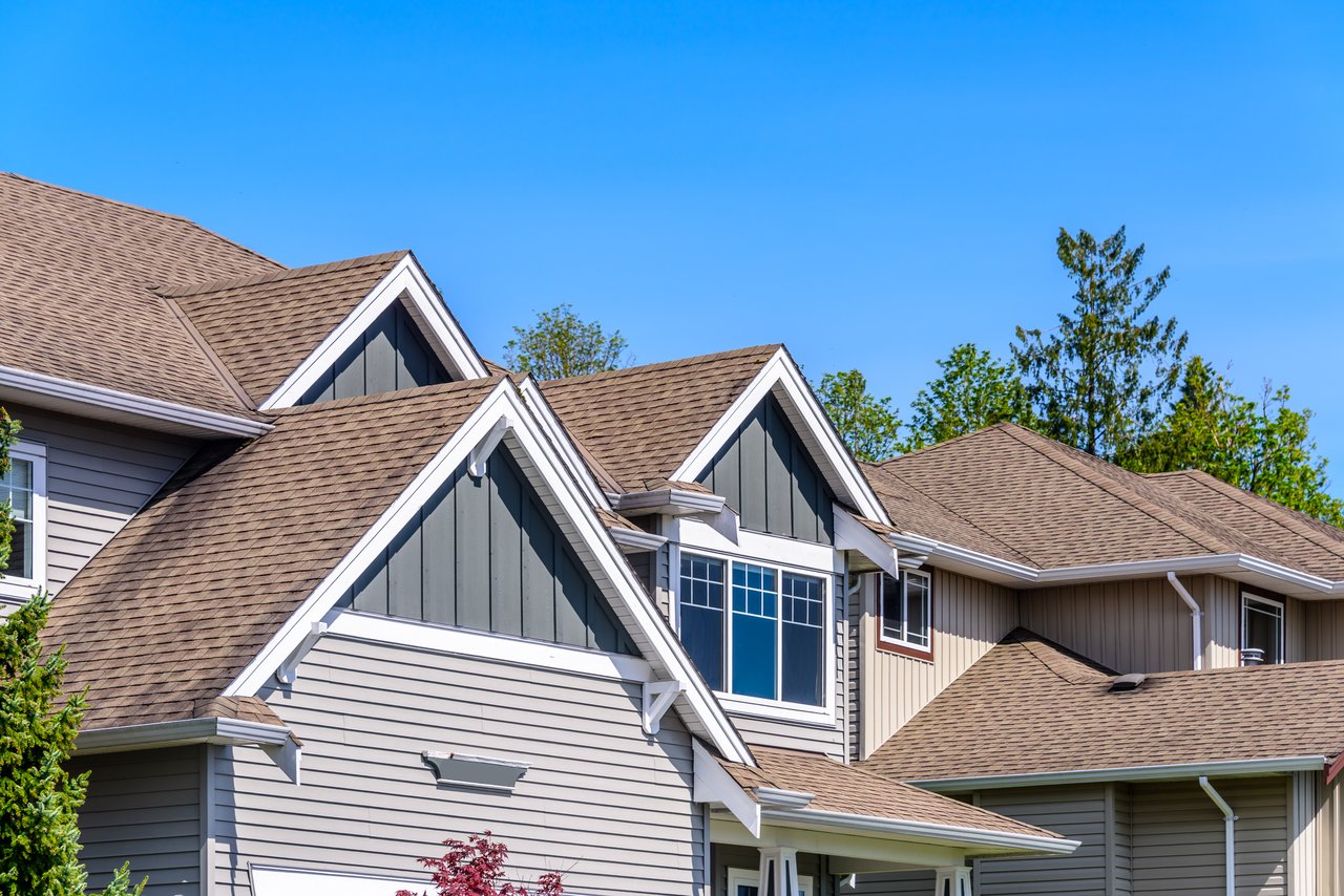 Suburban homes with steep shingle roofs, gray siding, and white-trimmed gables.