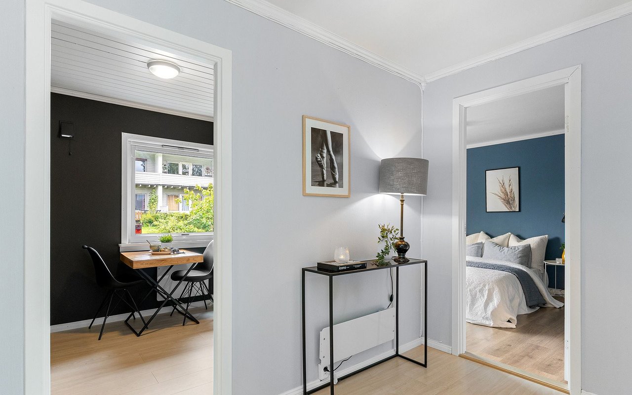 Apartment hallway with a console table between doorways to a dining nook and bedroom.