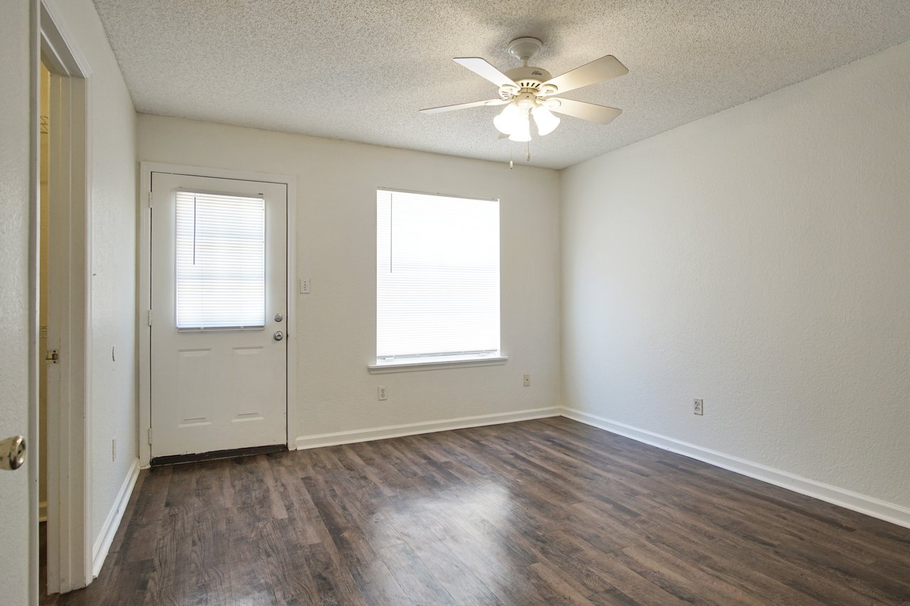 Empty room featuring hardwood floors and a ceiling fan, creating a spacious and airy atmosphere.