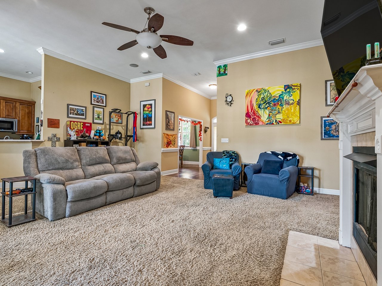 Living room with a gray sectional, blue armchairs, colorful wall art, and a white fireplace.