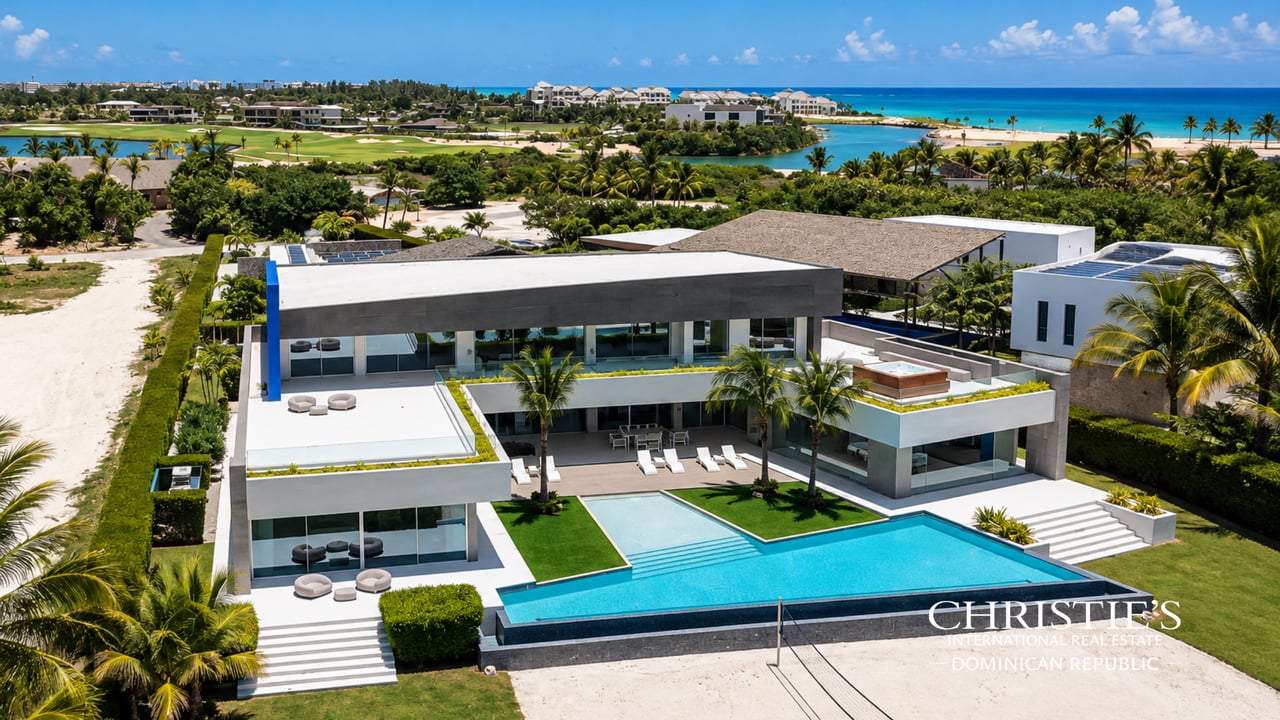 Modern oceanfront estate with a large pool, rooftop hot tub, tropical landscaping, and beach views.