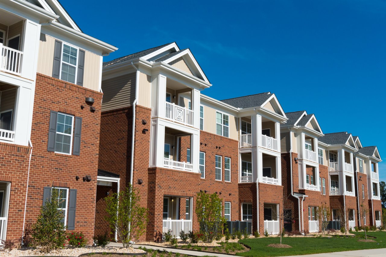 Condominium buildings with brick facades, white balconies, and landscaped grounds.