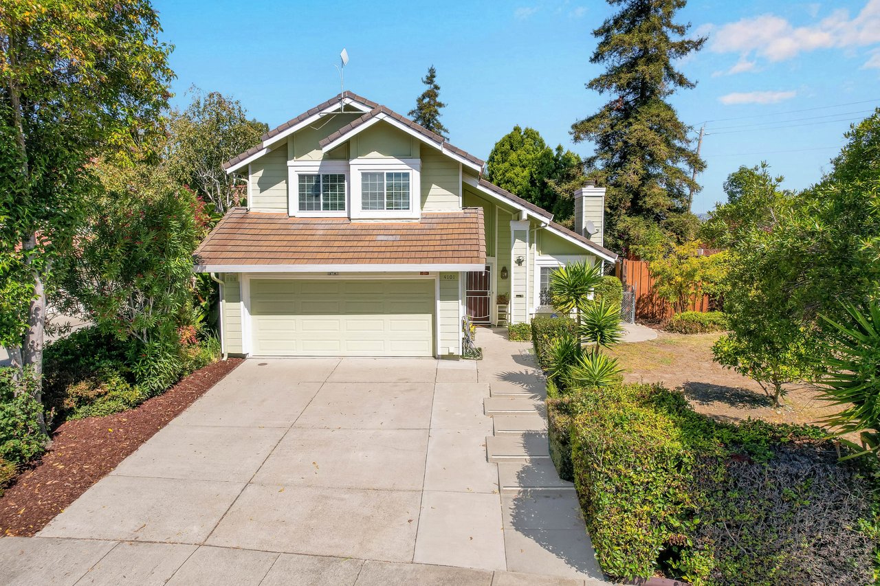 Two-story house with an attached garage, wide driveway, and landscaped front yard.