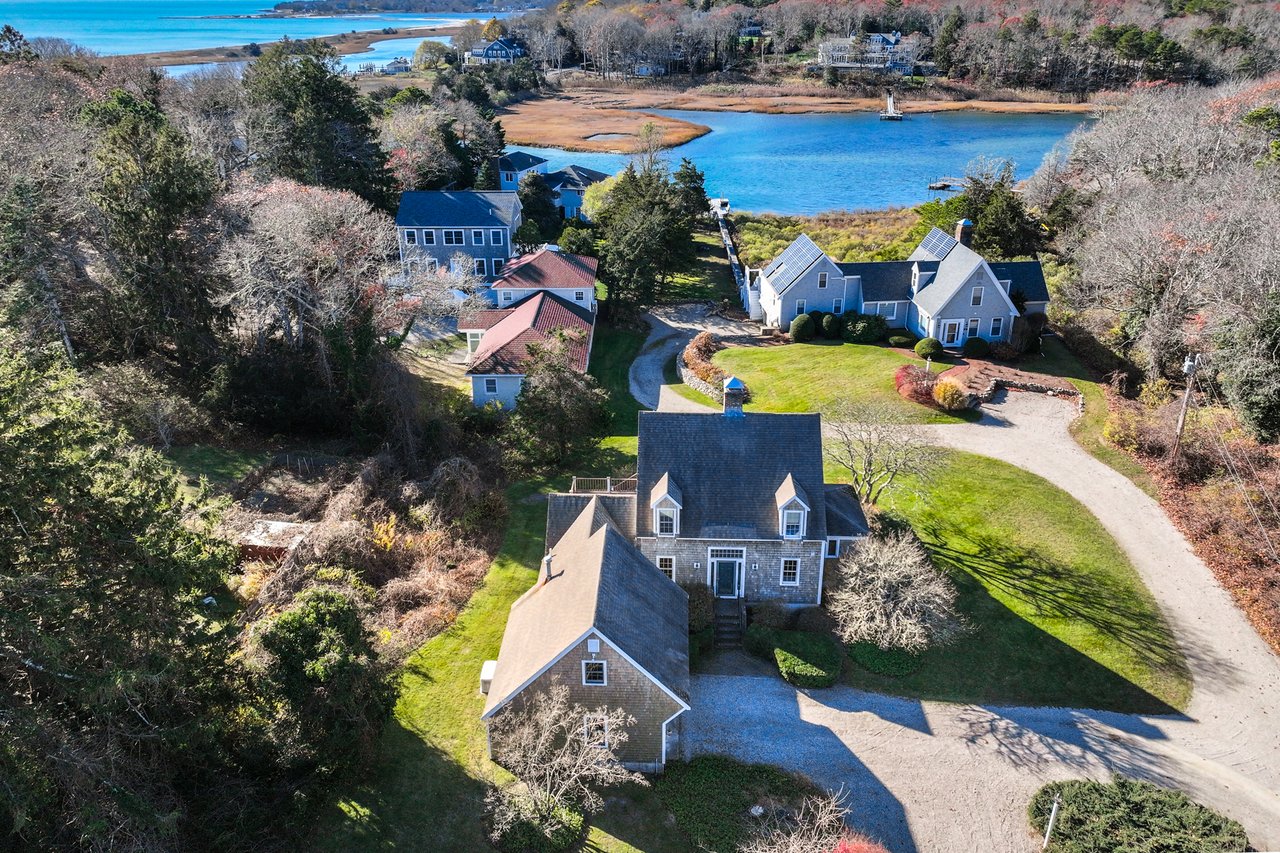 Aerial view of coastal homes beside an inlet, marsh, and ocean.