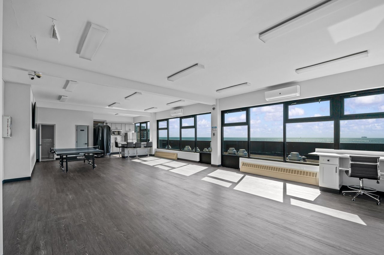 Shared recreation room with a ping-pong table, kitchenette, and wide ocean-view windows.