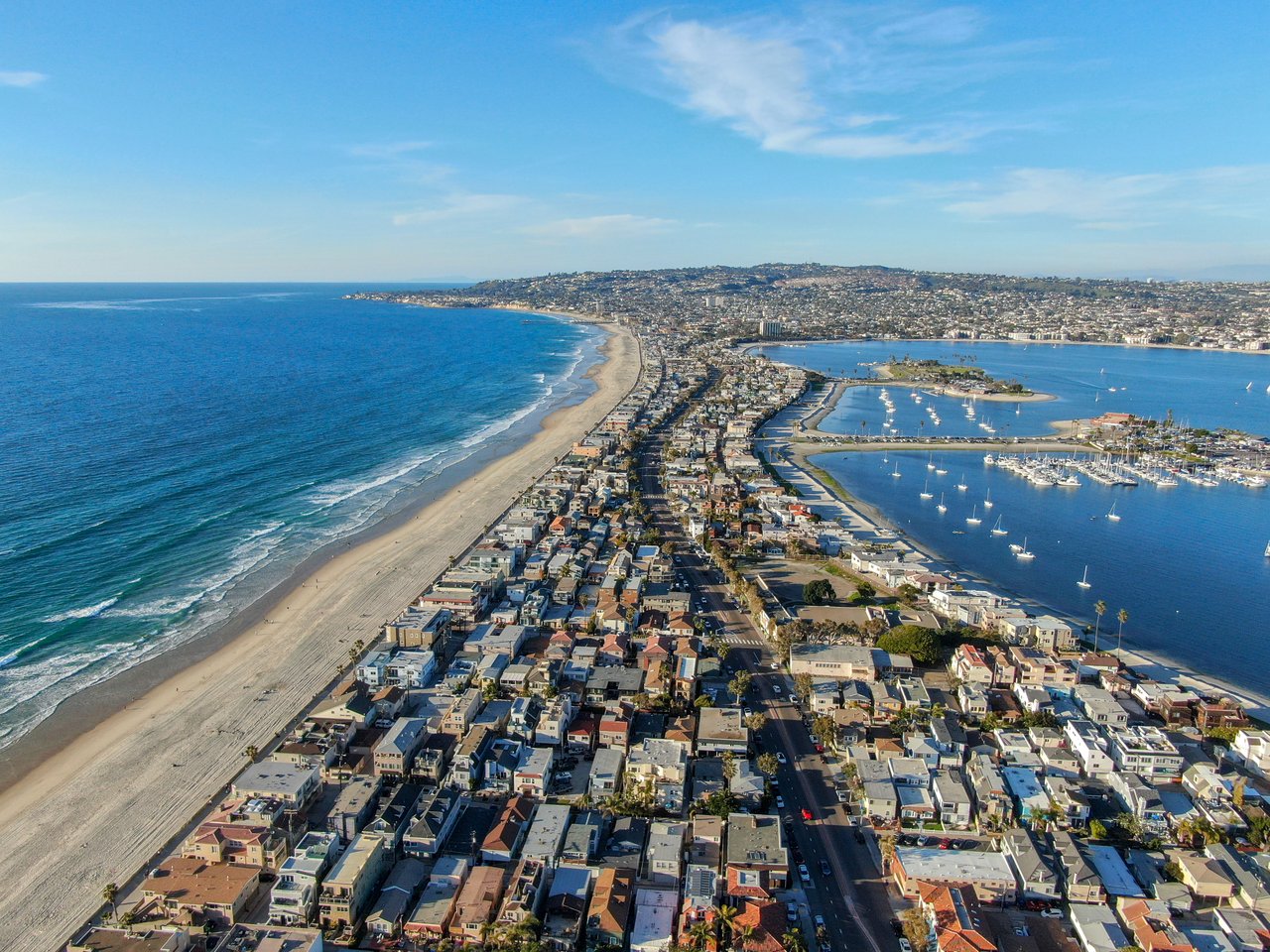 Aerial view of Mission Beach between the Pacific Ocean and sailboat-filled Mission Bay.