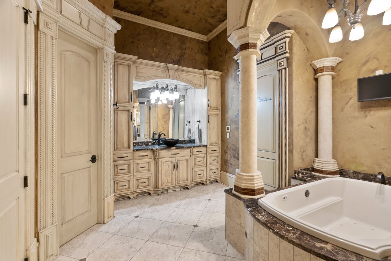 Primary bath with soaking tub, columns, dual vanities, and spa-style finishes.