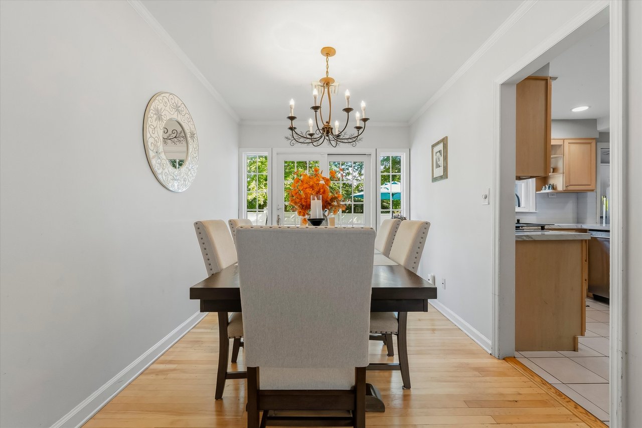 Dining room with a dark table, beige chairs, chandelier, and French doors.