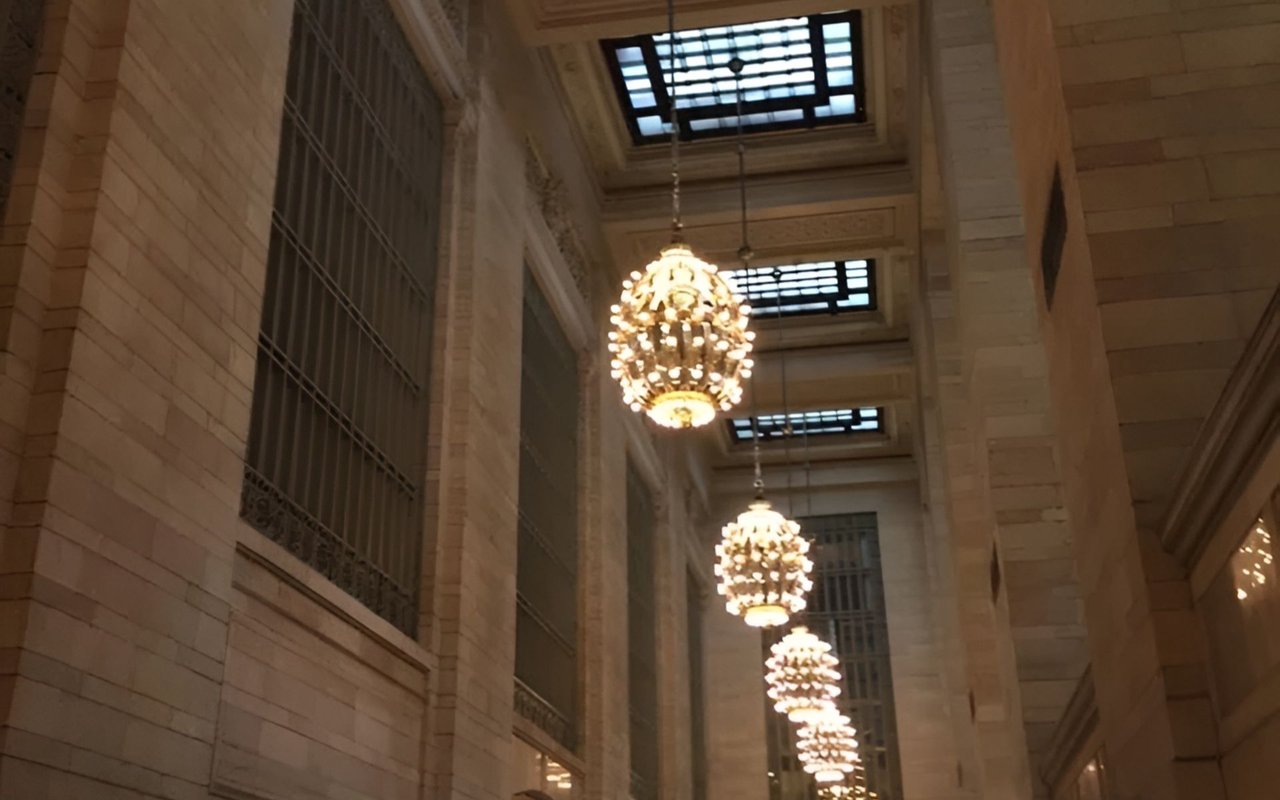 Stone atrium with ornate chandeliers, metal grilles, and skylights.