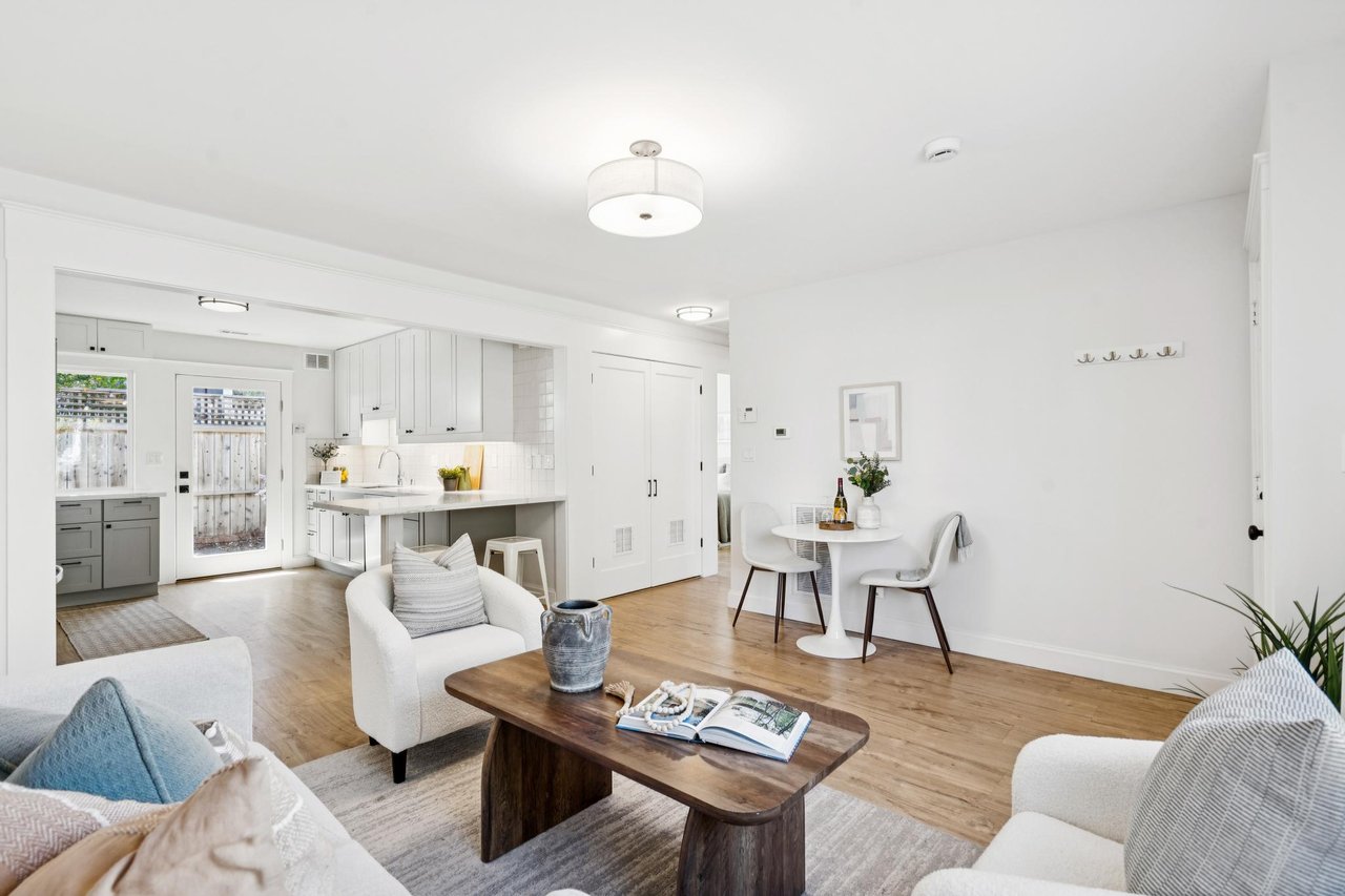 Open-plan living room with a wood coffee table, dining nook, and white kitchen.
