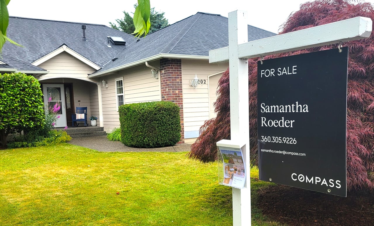 House with a Samantha Roeder for-sale sign beside the front lawn.